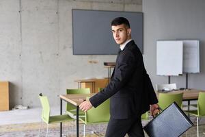 A determined businessman in a black suit confidently walks through the office, embodying professionalism and focus as he heads towards new challenges photo
