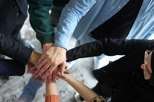 A top view of business people joining hands in a circle, symbolizing unity, collaboration, and shared success in the workplace photo