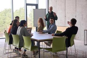 A young, diverse business team sitting together in a modern office, exchanging ideas and business plans, fostering collaboration and innovation for future success. photo