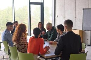 A young, diverse business team sitting together in a modern office, exchanging ideas and business plans, fostering collaboration and innovation for future success. photo