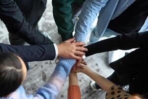 A top view of business people joining hands in a circle, symbolizing unity, collaboration, and shared success in the workplace photo