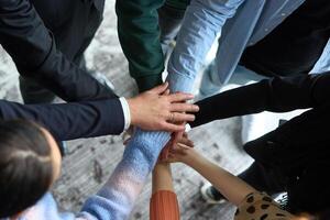 A top view of business people joining hands in a circle, symbolizing unity, collaboration, and shared success in the workplace photo