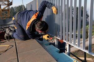 Industrial welder skillfully crafts a metal fence for a new business complex, using modern equipment that casts bright sparks and highlights the precision and dedication of the craft. photo