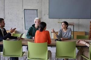 A young, diverse business team sitting together in a modern office, exchanging ideas and business plans, fostering collaboration and innovation for future success. photo