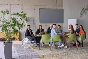 A diverse group of business professionals sitting in an office meeting with their director, who is in a wheelchair, fostering collaboration, leadership, and inclusivity photo