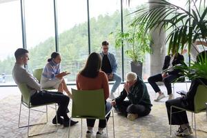 Corporate business team meeting with a manager or coach. Group of happy diverse, multiracial people sitting in a circle photo