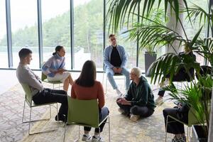 Corporate business team meeting with a manager or coach. Group of happy diverse, multiracial people sitting in a circle photo