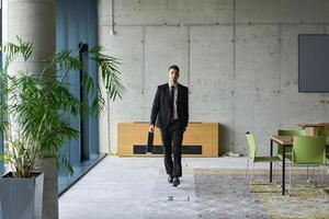A determined businessman in a black suit confidently walks through the office, embodying professionalism and focus as he heads towards new challenges photo