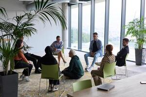 Corporate business team meeting with a manager or coach. Group of happy diverse, multiracial people sitting in a circle photo