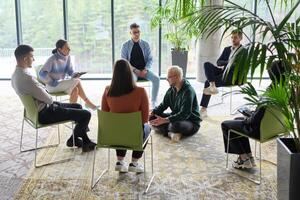 Corporate business team meeting with a manager or coach. Group of happy diverse, multiracial people sitting in a circle photo