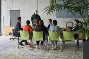 A young, diverse business team sitting together in a modern office, exchanging ideas and business plans, fostering collaboration and innovation for future success. photo