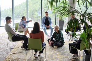Corporate business team meeting with a manager or coach. Group of happy diverse, multiracial people sitting in a circle photo