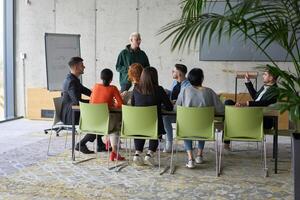 A young, diverse business team sitting together in a modern office, exchanging ideas and business plans, fostering collaboration and innovation for future success. photo