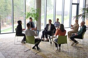 Corporate business team meeting with a manager or coach. Group of happy diverse, multiracial people sitting in a circle photo