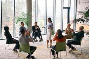 Corporate business team meeting with a manager or coach. Group of happy diverse, multiracial people sitting in a circle photo