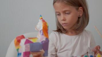 Cute seven-year-old girl creating art with paint at table video