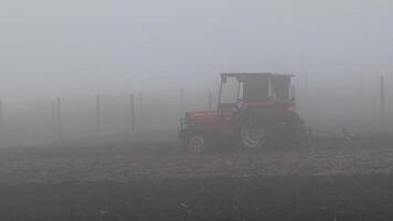 Vast Misty Field with a Vintage Tractor Amidst Foggy Conditions in the Morning Light video