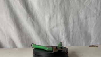 a green and black pliers standing on top of a black box video
