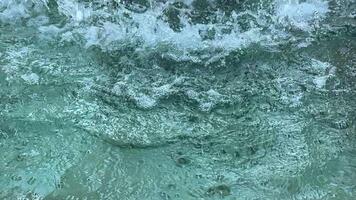 Close-up of the surface of the water with the flow falling into it, causing waves video