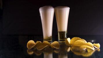 beer is pouring and foaming in a glass on green background with snacks. St Patricks Day concept. 4K. Copy space. video