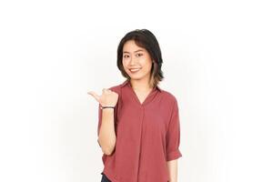 Showing and Pointing Product With Thumb Of Beautiful Asian Woman Isolated On White Background photo