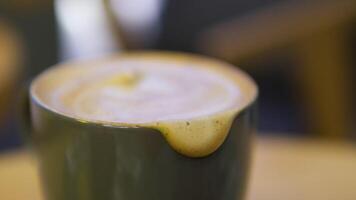 The features a latte coffee cup with a frothy layer on top, showcasing a perfect blend. A spoon rests inside the cup, inviting the viewer to savor the rich coffee. video