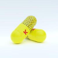 Vitamin K With Yellow Capsule, Granules and White Background photo