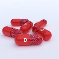 Vitamin D With Red Capsules, Granules and White Background photo