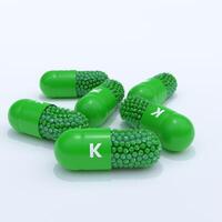 Vitamin K With Green Capsules, Granules and White Background photo