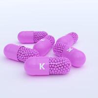 Vitamin K With Pink Capsules, Granules and White Background photo