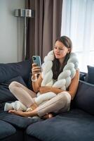 Young woman sits on a sofa with a weighted pillow on her shoulders and does a therapeutic practice aimed at getting rid of feelings of loneliness, session with a neurocoach. High quality photo