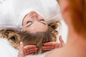 Healer performing by lightly touched set of 32 points of access bars on woman head, stimulating positive change thoughts and emotions. Alternative medicine. High quality photo