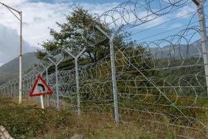 Border between Iran and Azerbaijan with barbed wire fence and mountainous backdrop photo