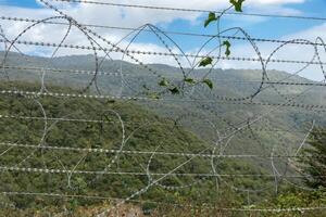 Border view between Iran and Azerbaijan with barbed wire and mountainous backdrop photo