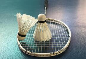 Broken badminton racket and used white badminton shuttlecocks on purple floor of the court, soft and selective focus, concept for badminton sport lovers around the world. photo