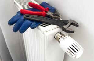 New thermostat, adjustable wrench and PTFE tape on the heating radiator. Installing a thermostat on a radiator for economical heating of an apartment. Plumbing work and service. photo