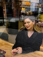 Young beautiful fashionable girl drinks coffee or tea in cafe. Model looking up. Copy, empty space for text photo