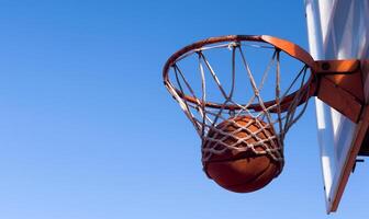 Bottom view of red basketball hoop with ball flying in. Copy space photo