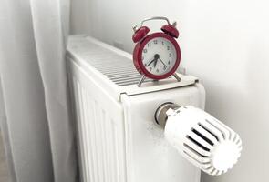 alarm clock on heating radiator against light background. Space for text. photo