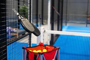 Paddle tennis. Padel racket and ball in front of an outdoor court. photo