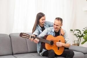 smiling father showing daughter how to play barre chord photo