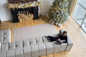 Happy female professional in talking to client over call while staying at home on Christmas. Cheerful business manager explaining new details of project on background of Christmas tree photo