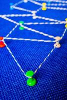 Network visualization with colored pins and string on blue fabric, connection concept photo