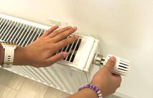 hand adjusting radiator temperature using thermostat. Home with central heating. photo