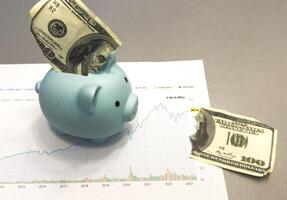 Piggy bank, coins, documents and calculator on the wooden table in the house. Concept of financial, savings, investments, funding. photo