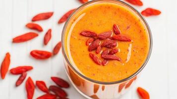 Bright orange smoothie topped with goji berries photo