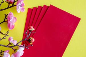 Top view of Chinese New Year with pink flower decoration with red packets on yellow cover background with customizable space for text. Chinese New Year celebration photo