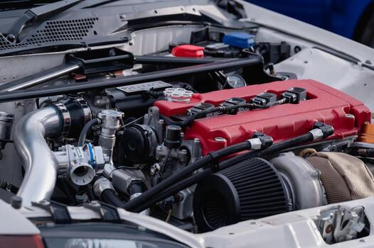 The engine of a car is shown in detail, with the hood open to reveal the inner workings. The engine is red and white, and it is a high-performance vehicle. Concept of power and speed photo