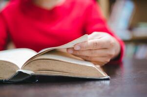 Close-up of hand turning pages in book, capturing quiet pleasure of reading scene radiates warmth and invites viewers to immerse themselves in literature photo