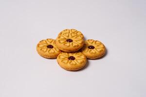 Side view of strawberry jam biscuits on white background, decorated with a circular heart motif on their surface. High resolution photo. photo